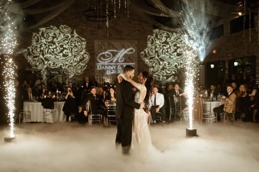 Wedding monogram projected on the wall behind a first dance with sparklers and fog