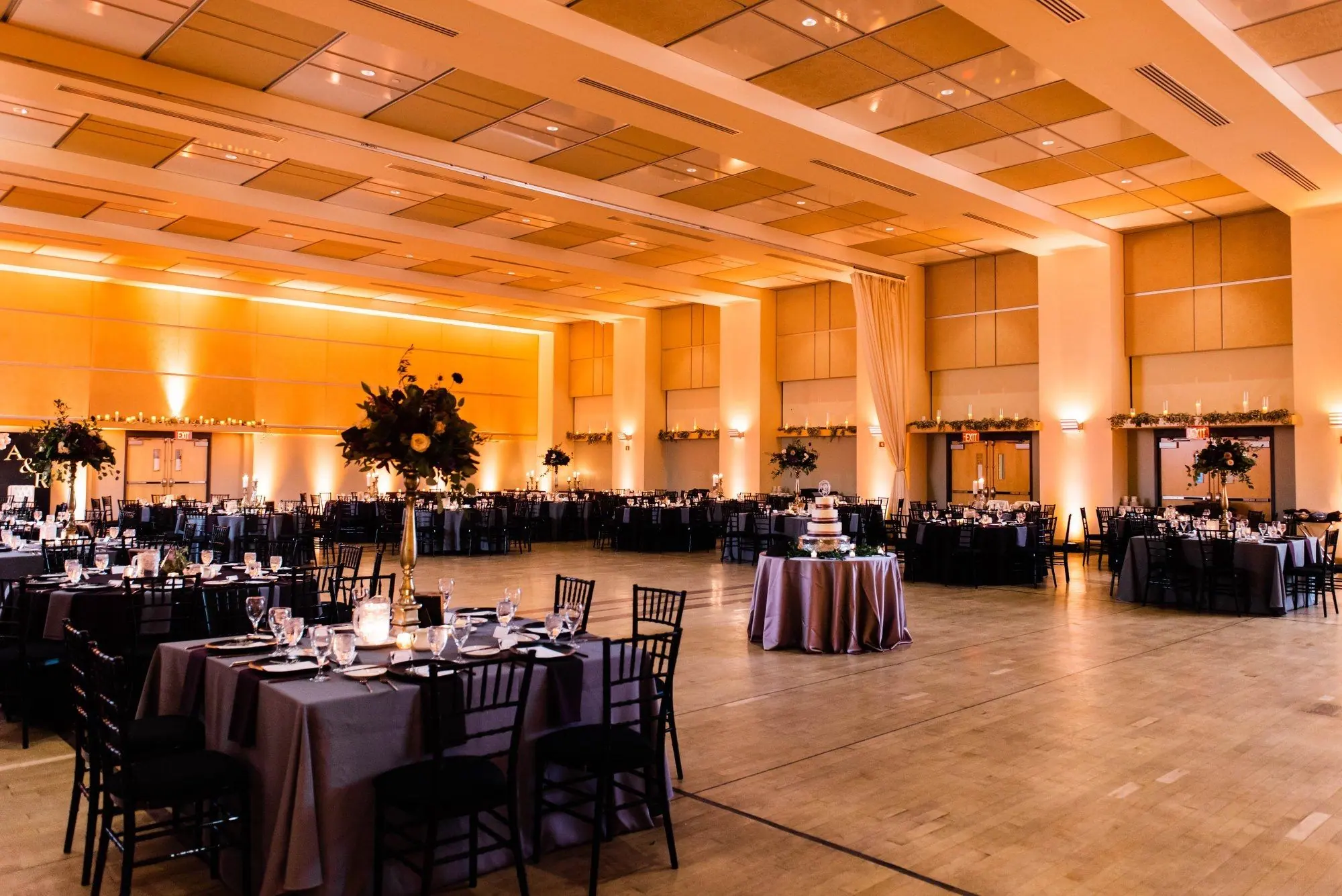 Wedding reception ballroom with amber uplighting and dinner tables
