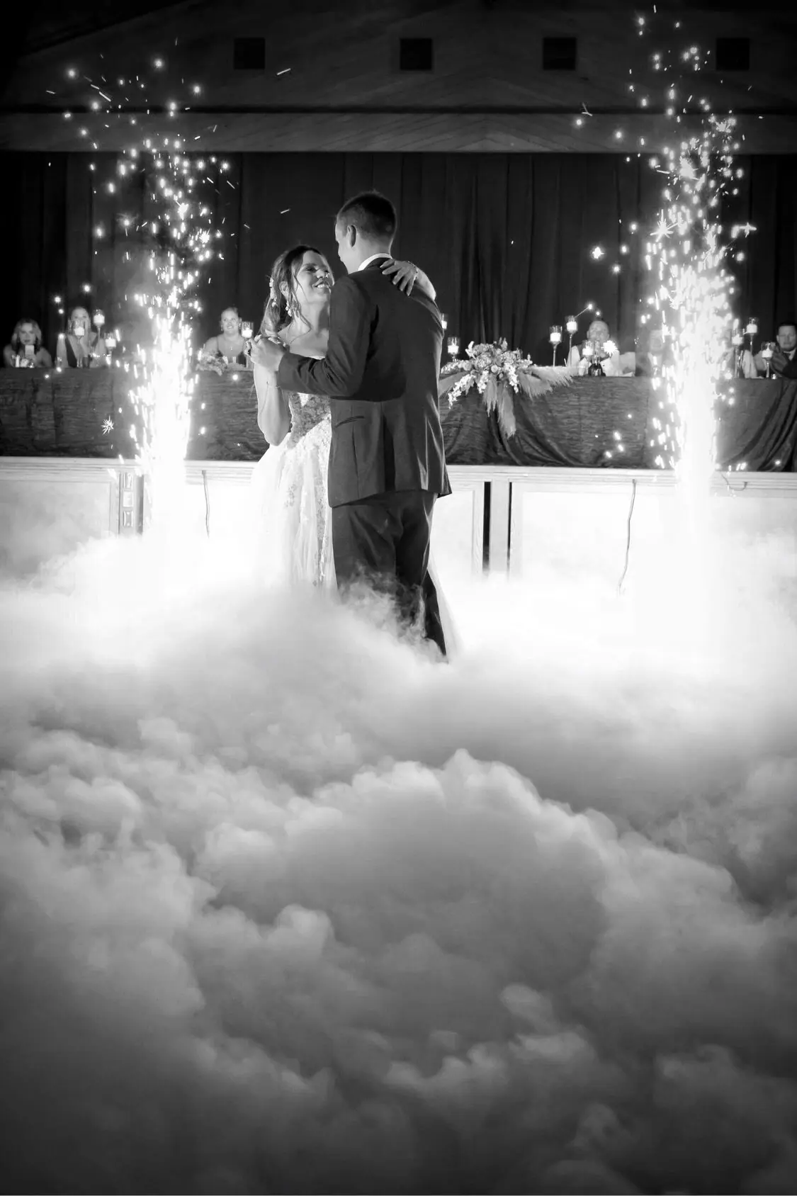 Black and white first dance in a low fog cloud with sparkler fountains behind the couple